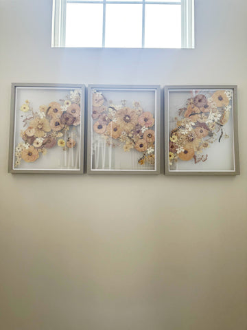 Amelia's 16x20 gray wood triptych pressed flower frame design hung up in her home.