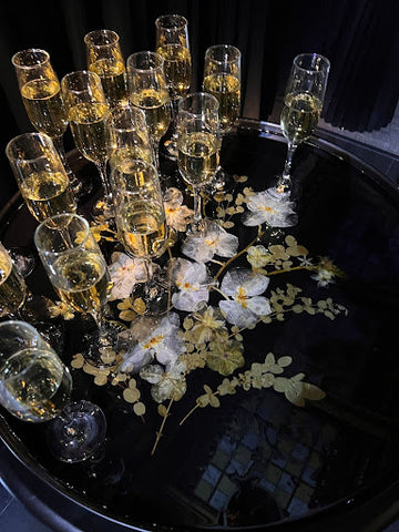 Pressed flowers in a resin tray serving champagne with drinnk charms attached to the glasses.