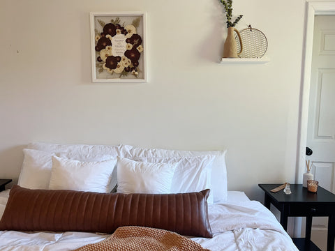 Pressed and framed wedding bouquet hanging above a bed. 