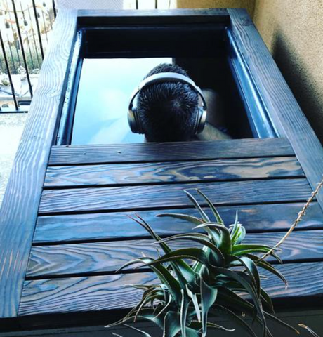 Man with headphones on cold plunging outdoors in a RENU Therapy cold plunge tank