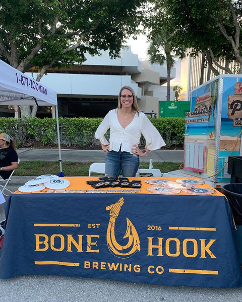 Bone Hook Brewing Co. farmers market booth with a representative showcasing their brand