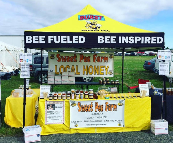 Sweet Pea Farm stall selling local honey under a yellow 'BURST Energy Gel' tent with the slogans 'BEE FUELED' and 'BEE INSPIRED'.