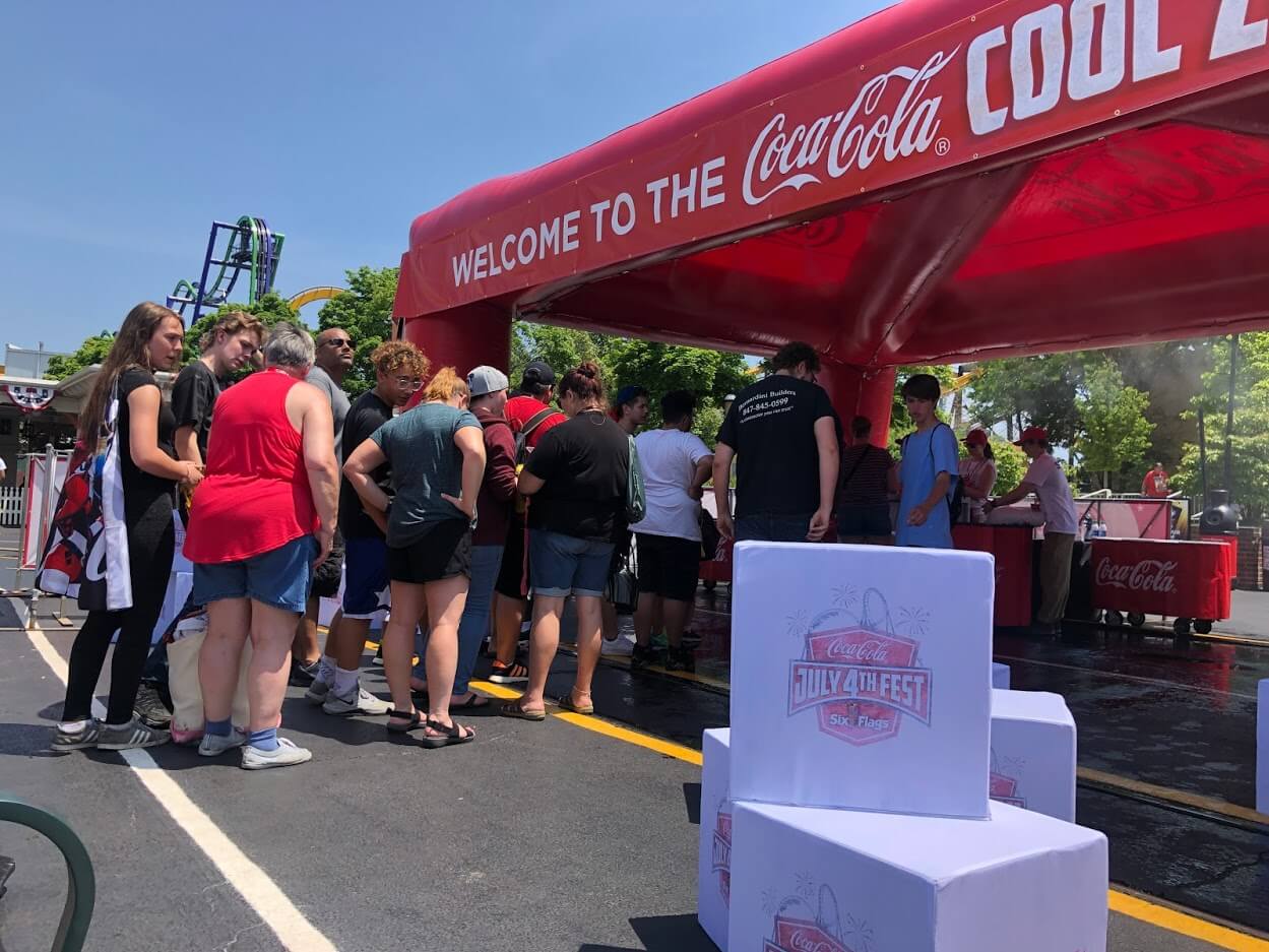Coca-cola branded misting inflatable tent with crowd lining up for beverages on a hot sunny day