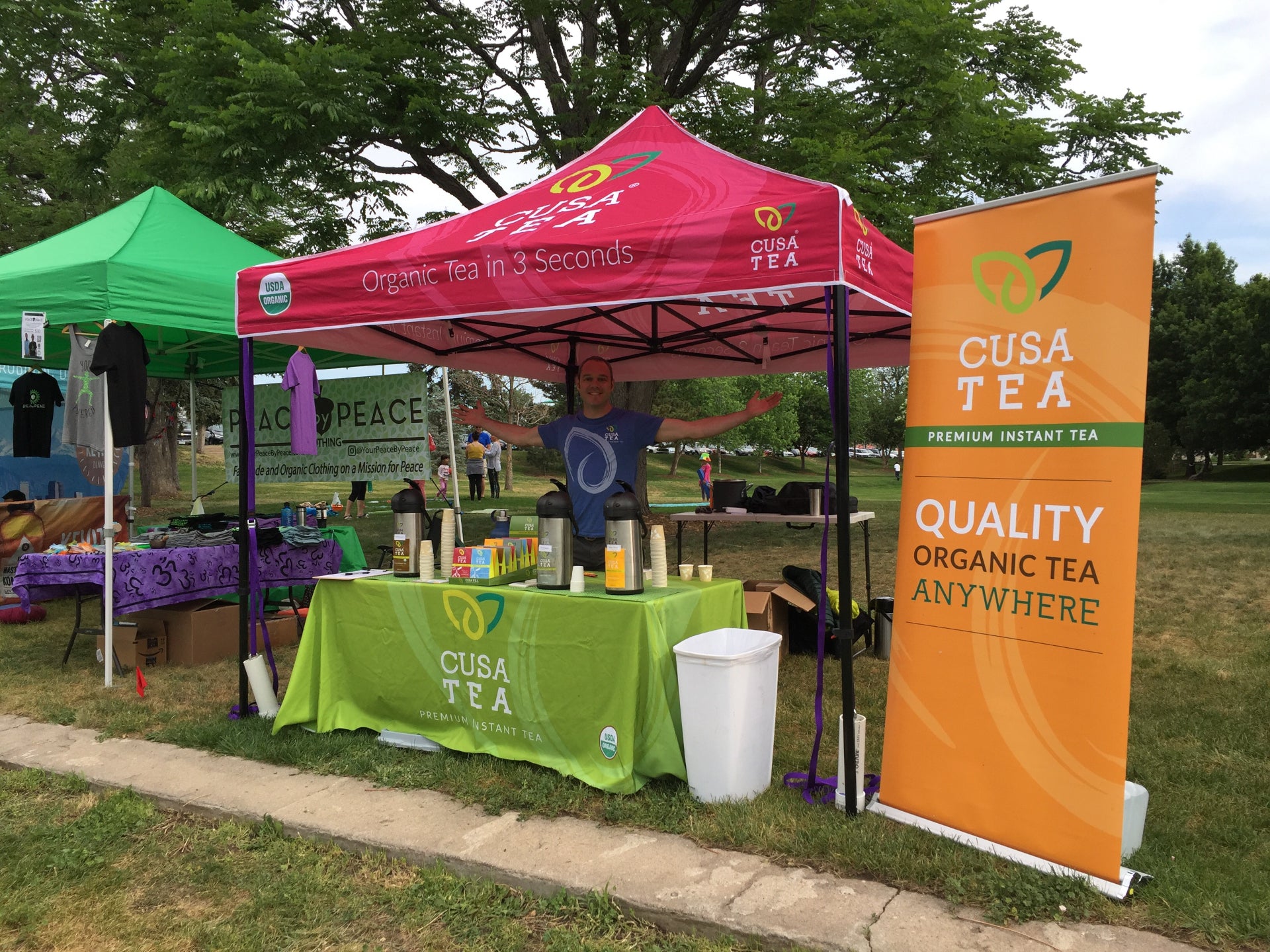 cusa tea's outdoor vendor booth with custom canopy tent, table with product displays and roll up banner