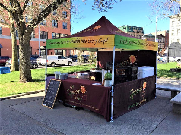 Squeeze Juices & Smoothies booth in a park, offering fresh-squeezed beverages with a focus on health and love