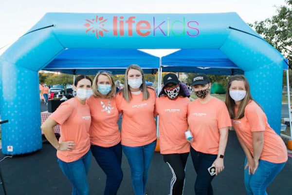 people pose for photo at Life Kids inflatable arch