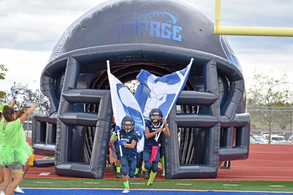 football players running through gray custom inflatable football helmet