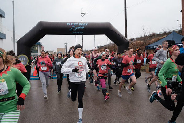 marathoners crossing start line with black inflatable arch