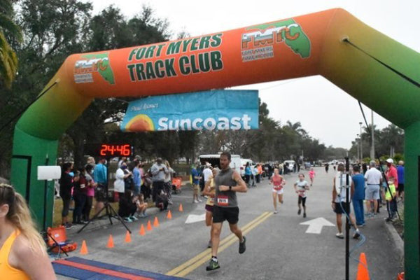 participant crosses finish line marked by branded arch