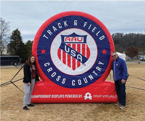 two people pose for photo at AAU’s custom inflatable