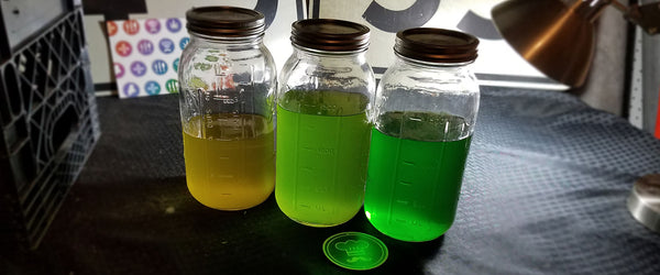 jars of various finished cannabis tinctures displaying differing shades of golden yellow and lime green