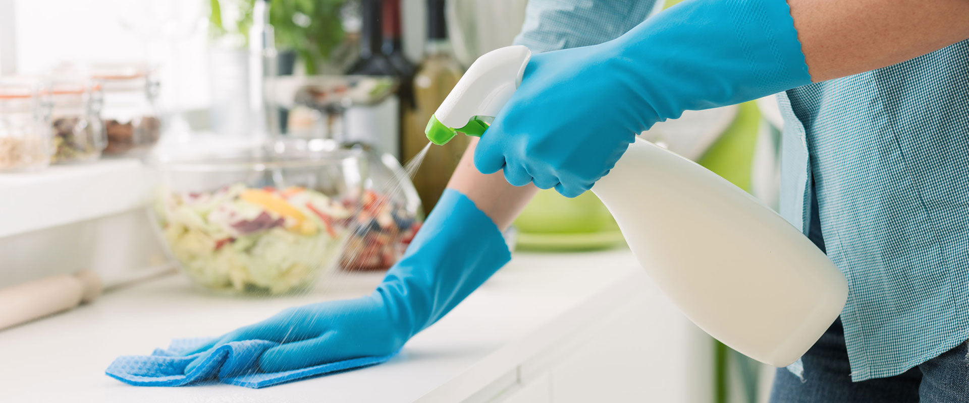 Person wearing gloves disinfecting a surface