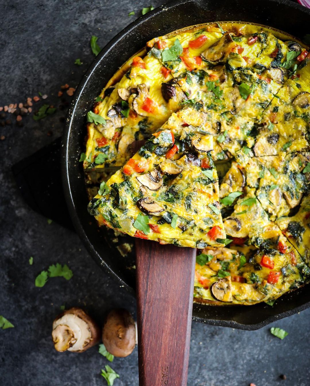 Scraping spinach and mushroom frittata using wooden spatula