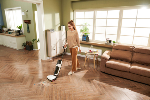 Une femme nettoie son salon avec l'aspirateur eau et poussière Dyad Pro de Roborock.