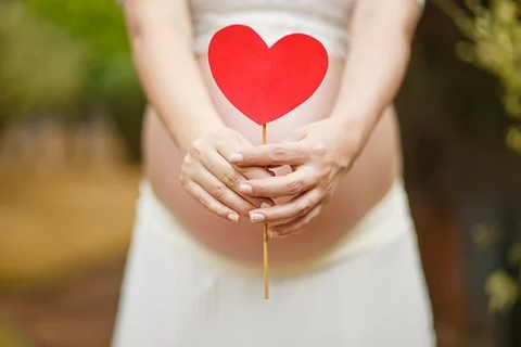 Pregnant Woman Holding Heart Sign