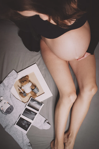 overhead shot of woman sitting on bed with ultrasound