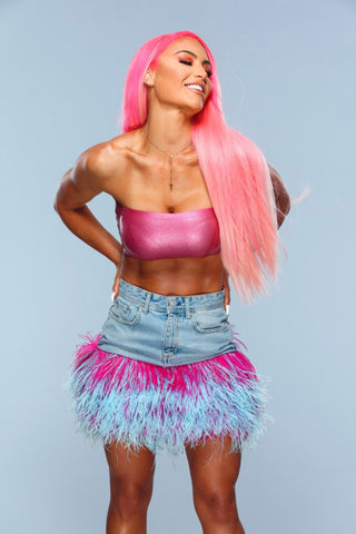 Woman posing with her hands on her hips, long pink hair, pink Vex tube top and a denim skirt smiling