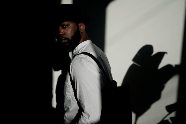 Male model standing in the sunlight wearing a leather backpack