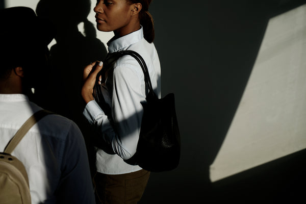 Female model standing in sunlight wearing a leather backpack