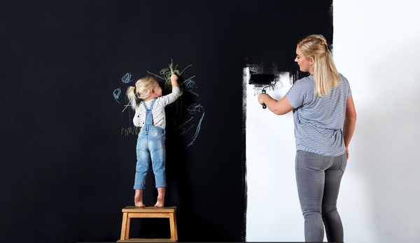 Woman and cild painting blackboard paint on the wall