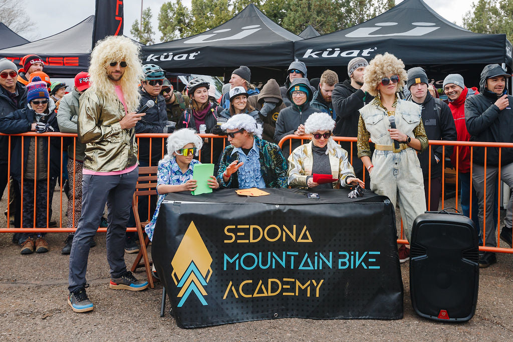 A group of men and women dressed in wigs and sunglasses ready to judge the Sedona Mountain Bike Festival Bunny Hop Challenge.