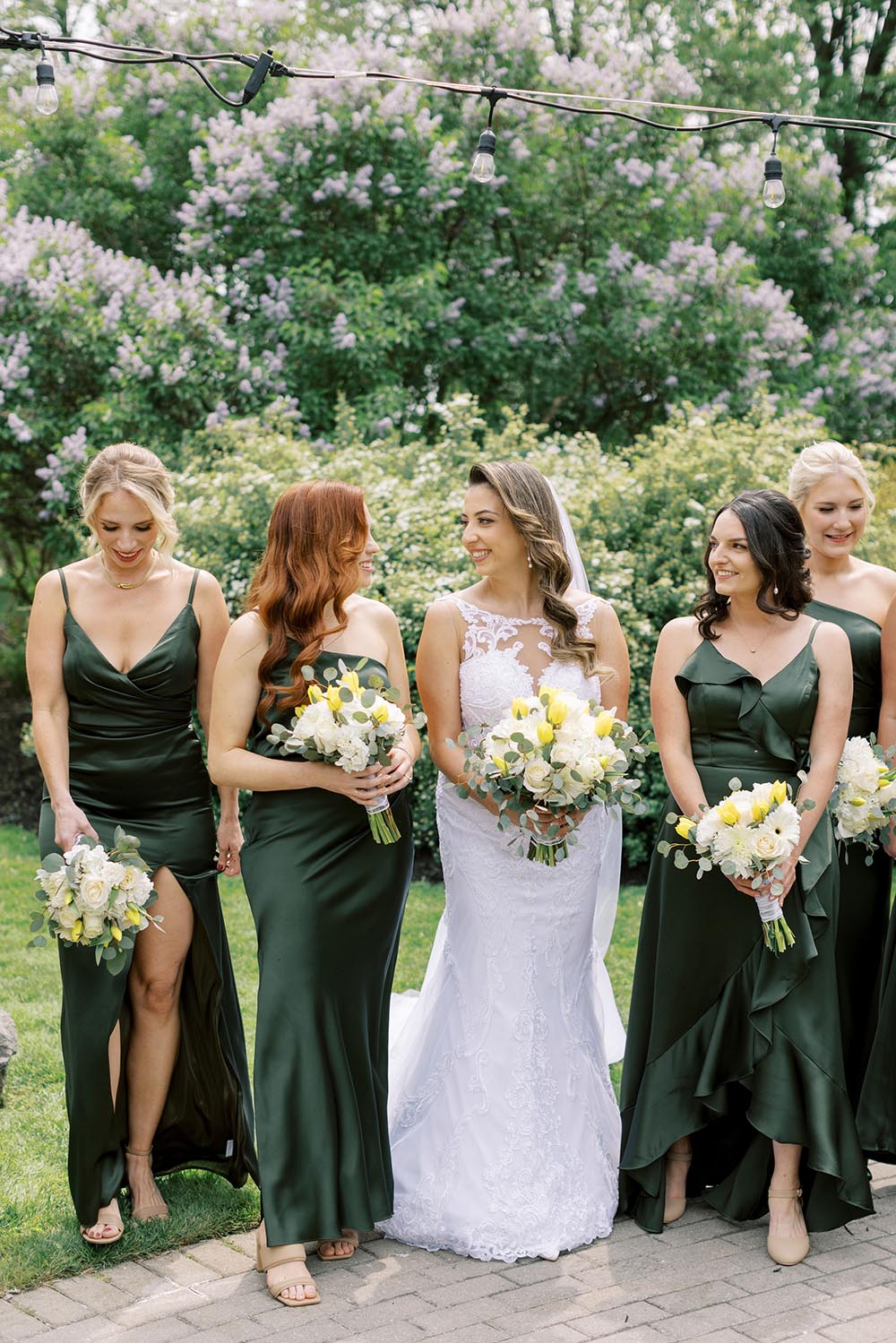 A bride and her bridesmaids walk through the beautiful gardens of a luxury hotel wedding