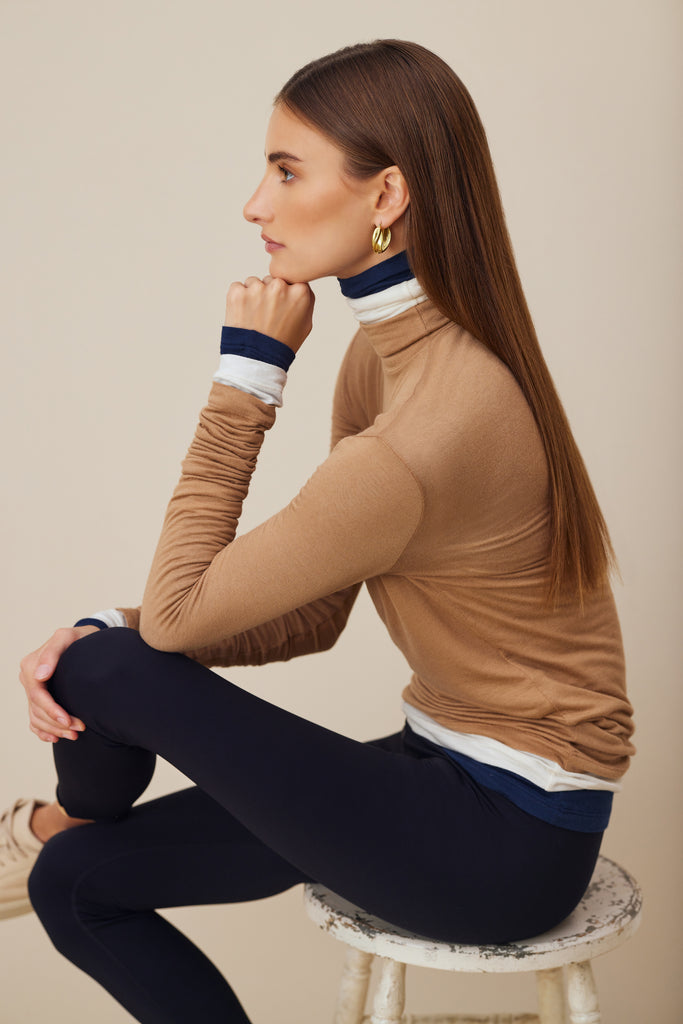 A woman sitting wearing a cashmere turtleneck