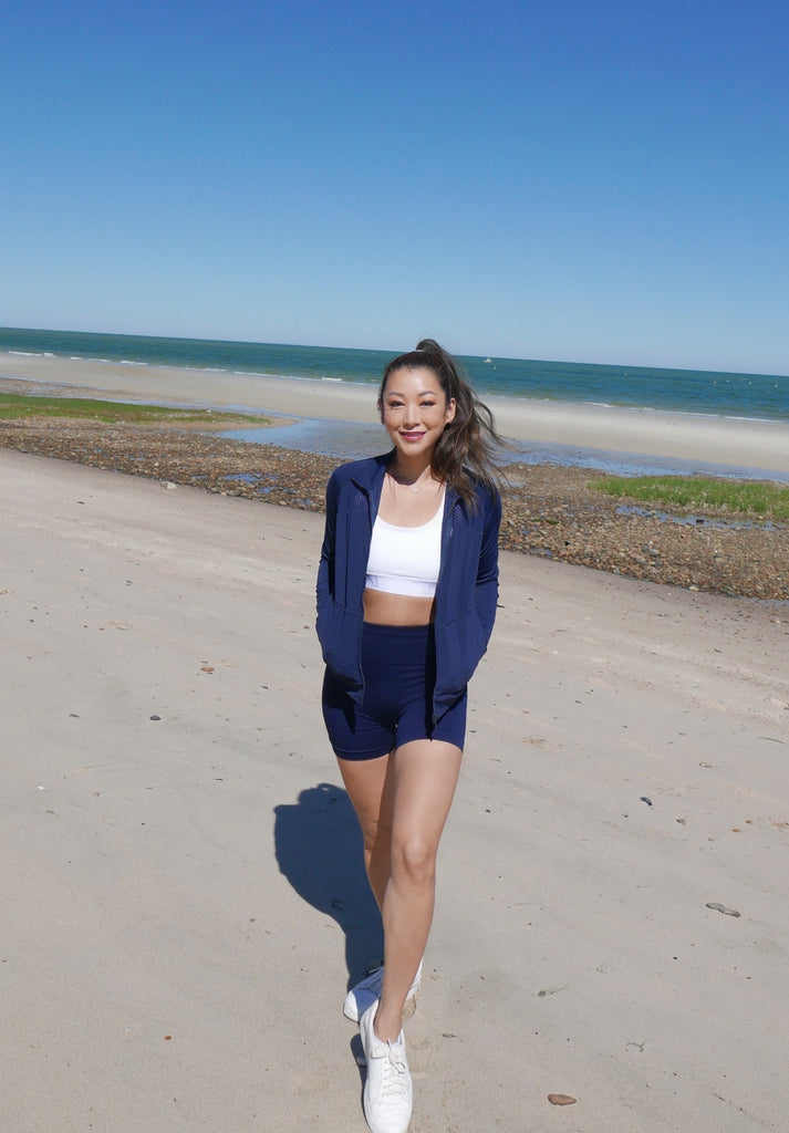 Woman on beach wearing Alala navy track jacket