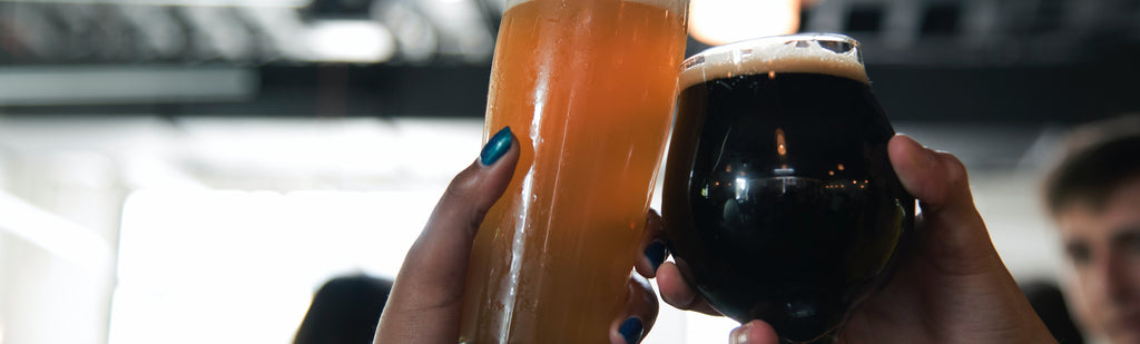 Two people holding glasses of beer