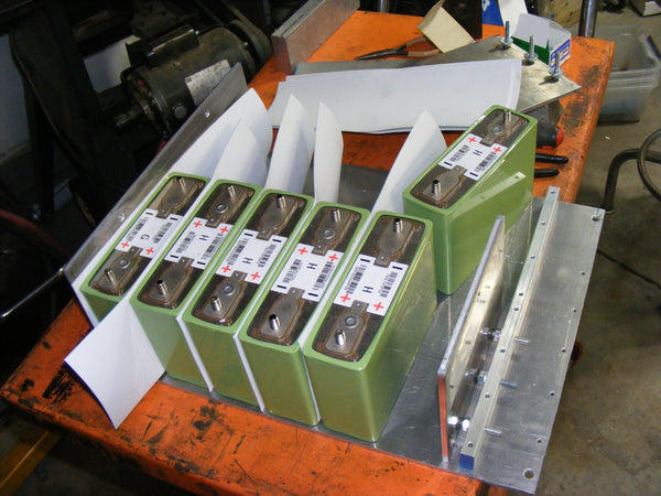 1/4” thick 6061 aluminum, batteries in a 2 by 6 configuration separated by 1/16” high density foam sheets