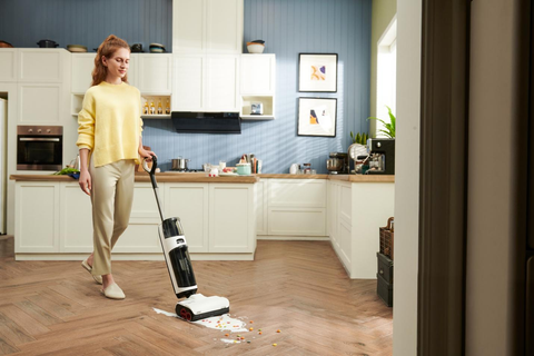 Frau benutzt einen Roborock Staubsauger, um auf dem Boden verschüttete Müsli-Flakes zu reinigen.