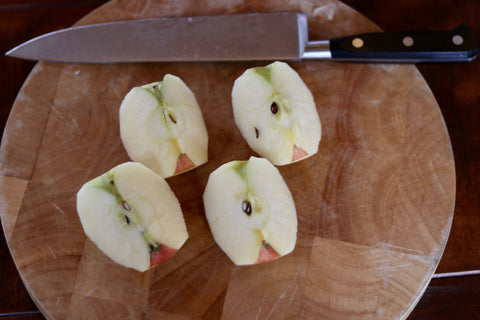 An apple quartered with a chef's knife