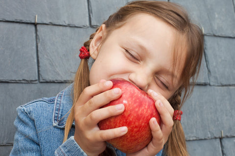 Young girl biting into a juicy organic apple