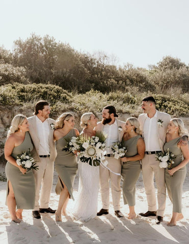 bridal party on beach bridesmaids wearing sage green and groomsmen wearing white and beige suits