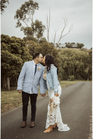 bride and groom kissing on road wearing bride pearl denim jacket