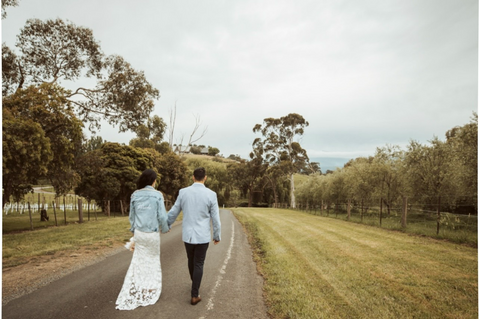 bride and groom walking away on road wearing bride pearl denim jacket