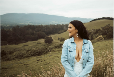 bride wearing bride pearl denim jacket looking back at country setting