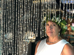 lady with flower crown on her head standing in front of a black pearl curtain