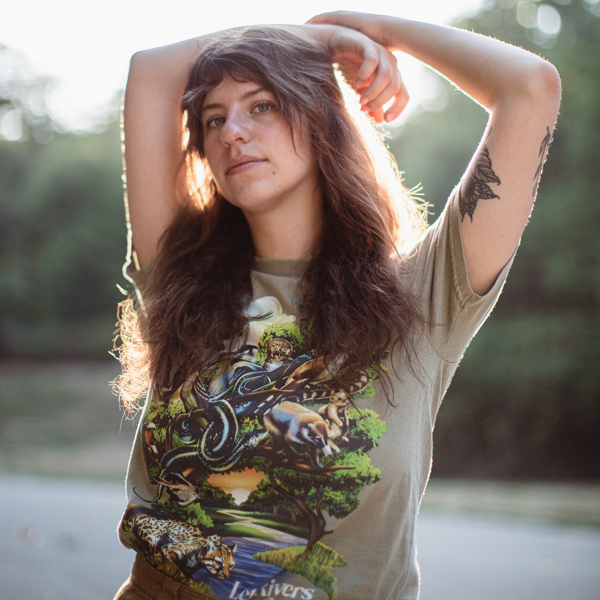 Photo of a woman wearing a shirt with a river and several species around it.