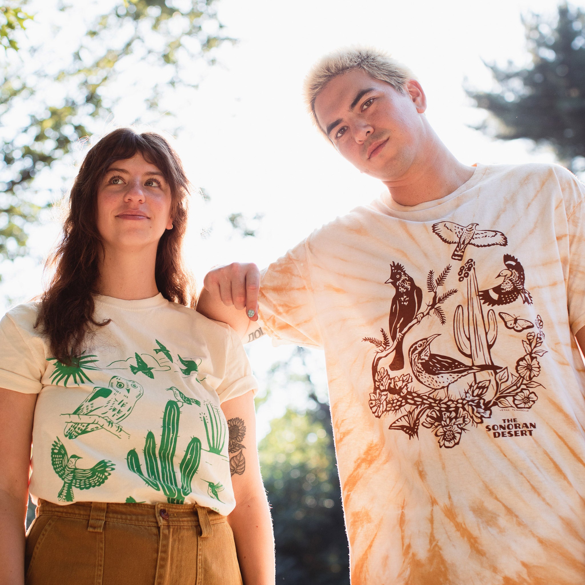 A man and woman wearing T-shirts with a variety of bird and plant species