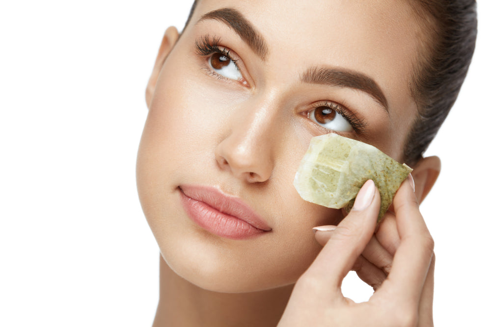 Woman holding a tea bag under her eye.