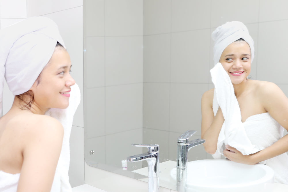 Brunette woman drying her face with a towel.