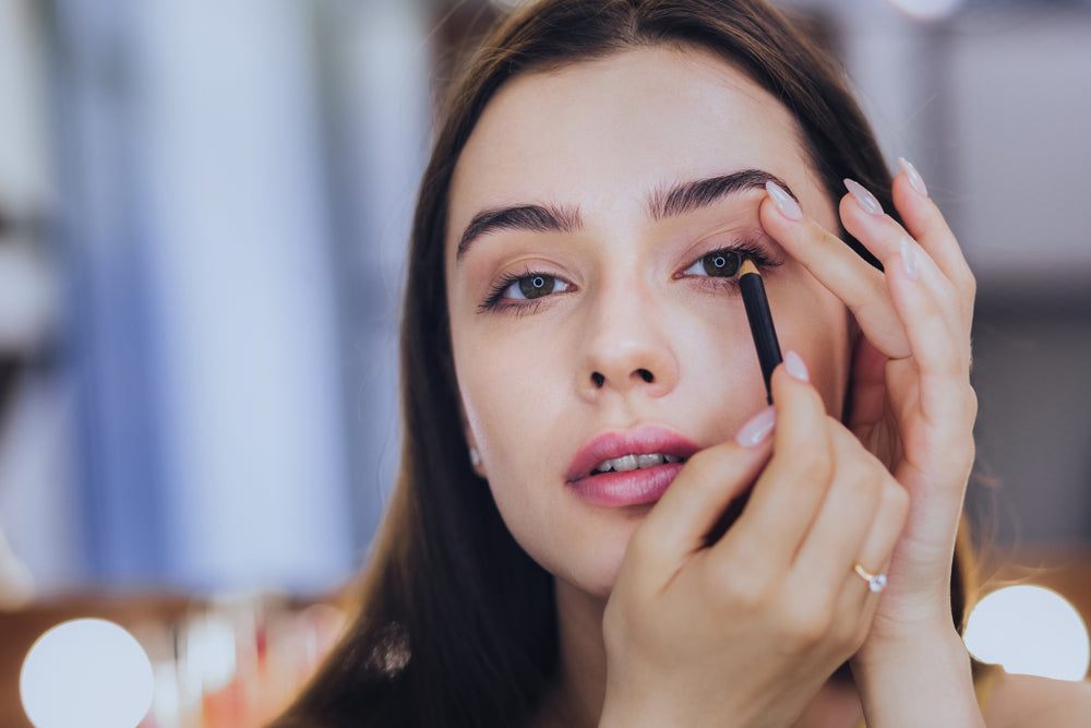 Woman carefully drawing eyeliner on her eyelids