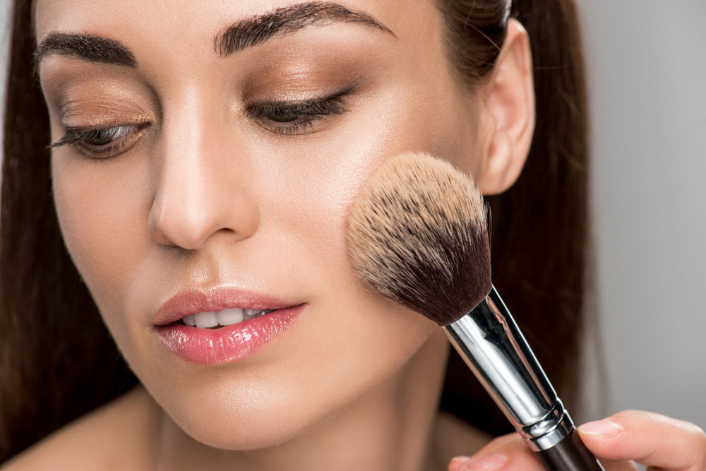 Woman applying face powder to her cheek.