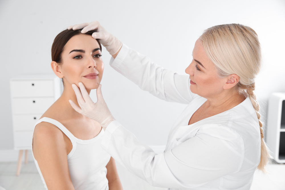 Dermatologist examining woman's face to provide skin care recommendations.