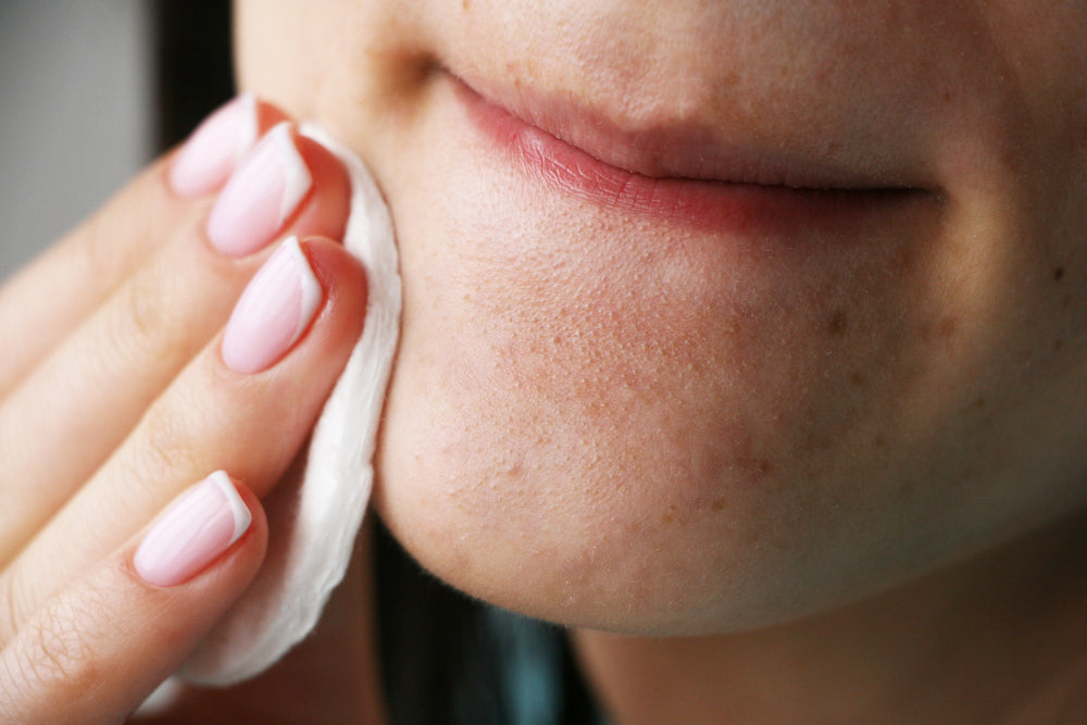 Close up of a woman rubbing her chin with a cleansing pad.