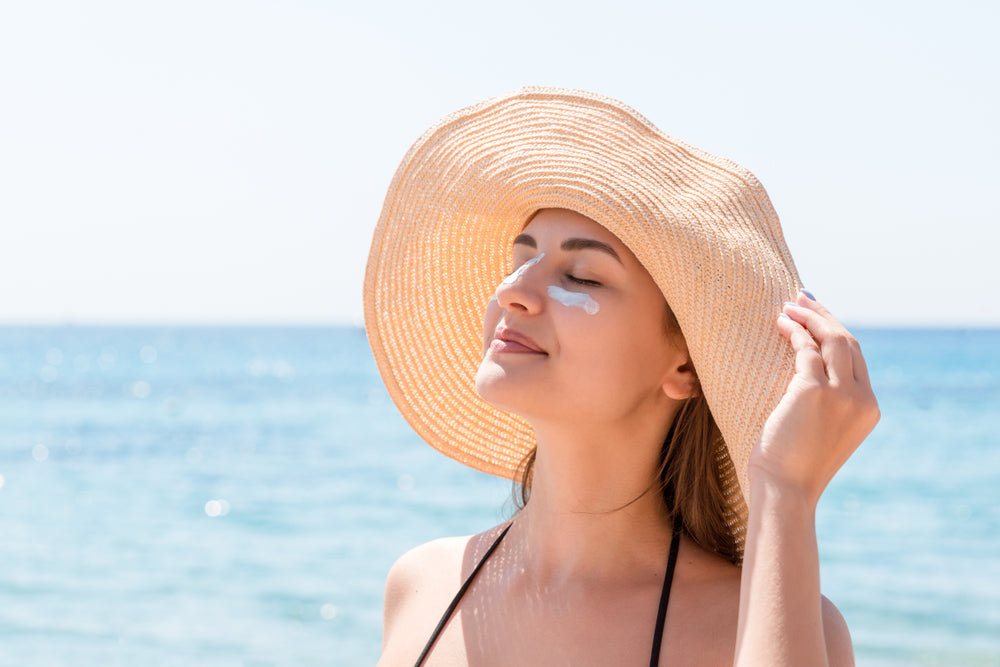 Woman at the beach wearing a sun hat and under eye skin care product