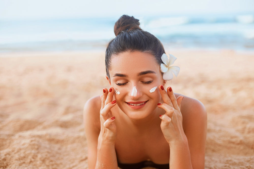 Woman at beach applying sunscreen to help acne and prevent sunburn