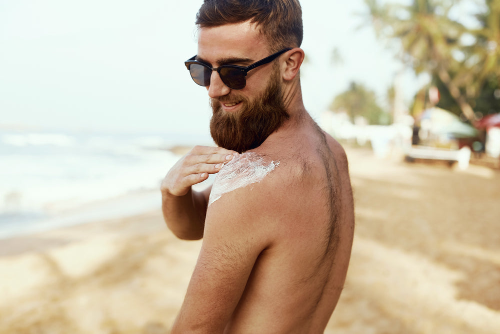 Man applying body sunscreen on his shoulder