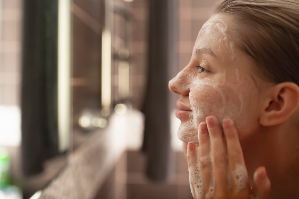 Young white woman applying cleanser to her face.